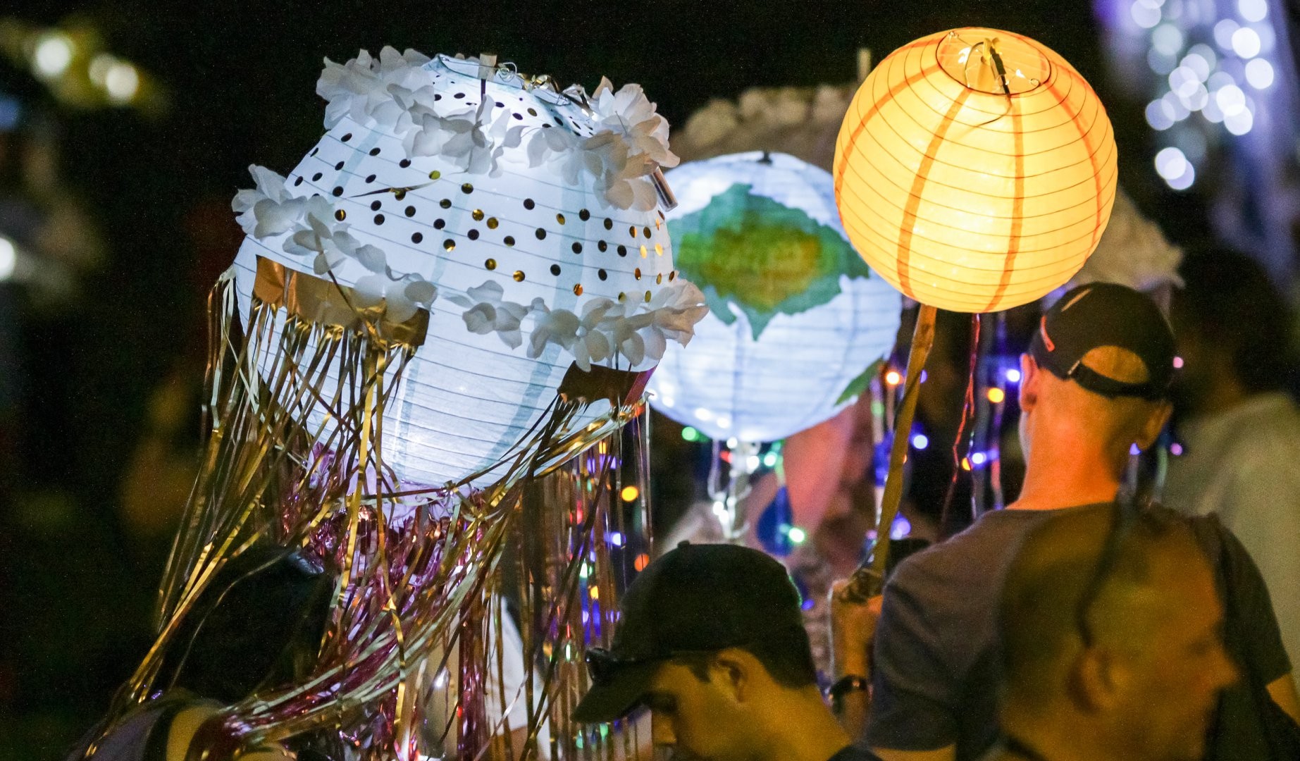 Handmade jellyfish-style lanterns with tinsel and paper shades glowing at the night parade